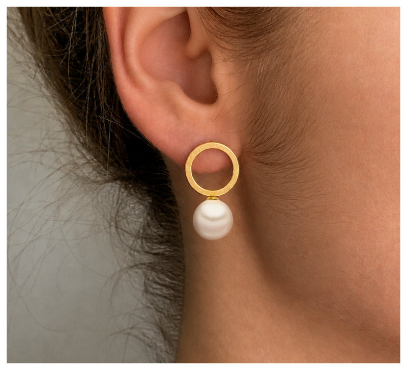 Circle Ohrring mit Goldauflage und Muschelkernperle, am Ohr getragen.