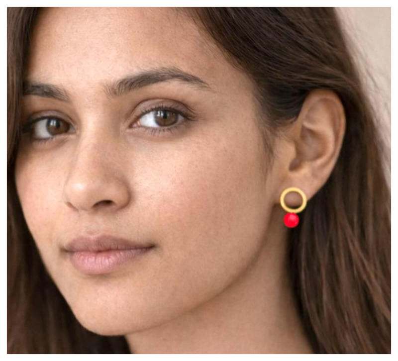 Porträt einer Frau mit Doll Up Sister Ohrringen „Smilla“: goldfarbener Kreis-Ohrstecker mit roter Neonperle, getragen am Ohr.