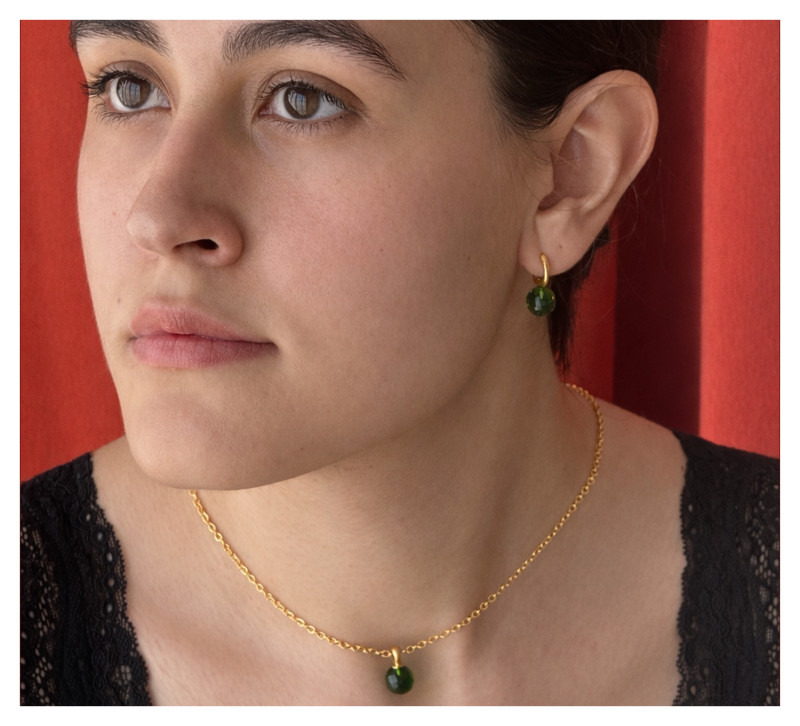 Model im Profil mit „Luna Orb“ Ohrringen in Grün.