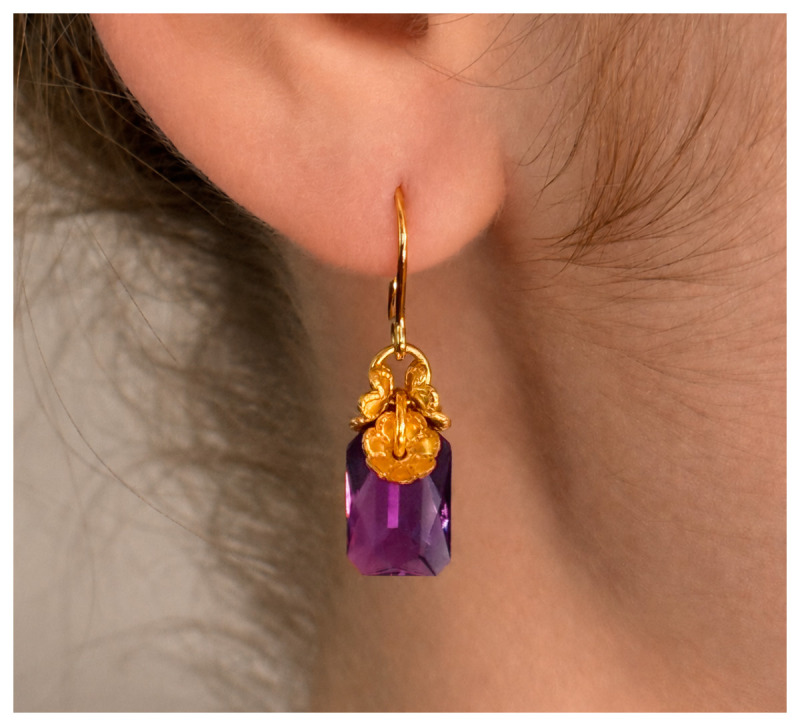 Modell mit „Milia“ Ohrringen mit Goldauflage und Kristallglasstein.